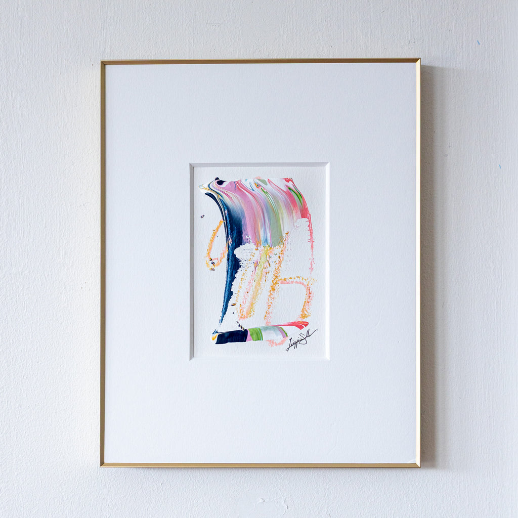 Framed abstract artwork with colorful brush strokes on a white wall