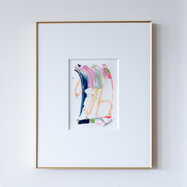 Framed abstract artwork with colorful brush strokes on a white wall