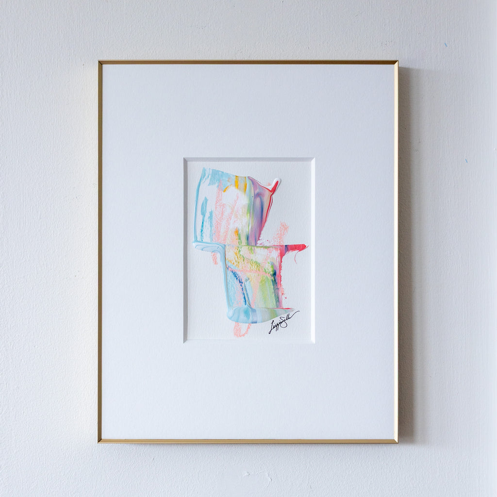 Framed abstract art painting with colorful shapes on a white wall