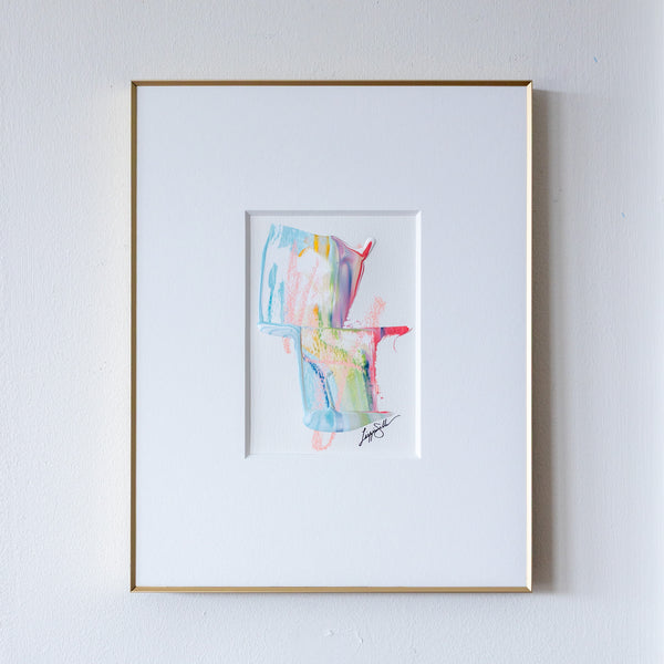 Framed abstract art painting with colorful shapes on a white wall