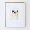 A framed abstract art print featuring colorful vertical brushstrokes in gold, pink, blue, and black on a white mat, enclosed in a thin gold frame and hung on a white textured wall.