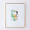 A framed abstract art print featuring green, orange, and black paint strokes on a white mat, enclosed in a thin gold frame against a white wall.