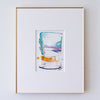 A framed abstract painting, set in a white mat and a thin gold frame against a white wall.