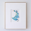 A framed abstract artwork, set in a white mat and a thin gold frame against a white wall.