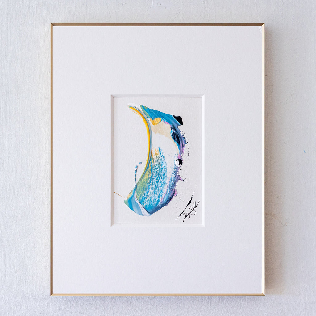 A framed acrylic painting, featuring a wide white mat board and a thin gold frame, mounted on a light gray textured wall.