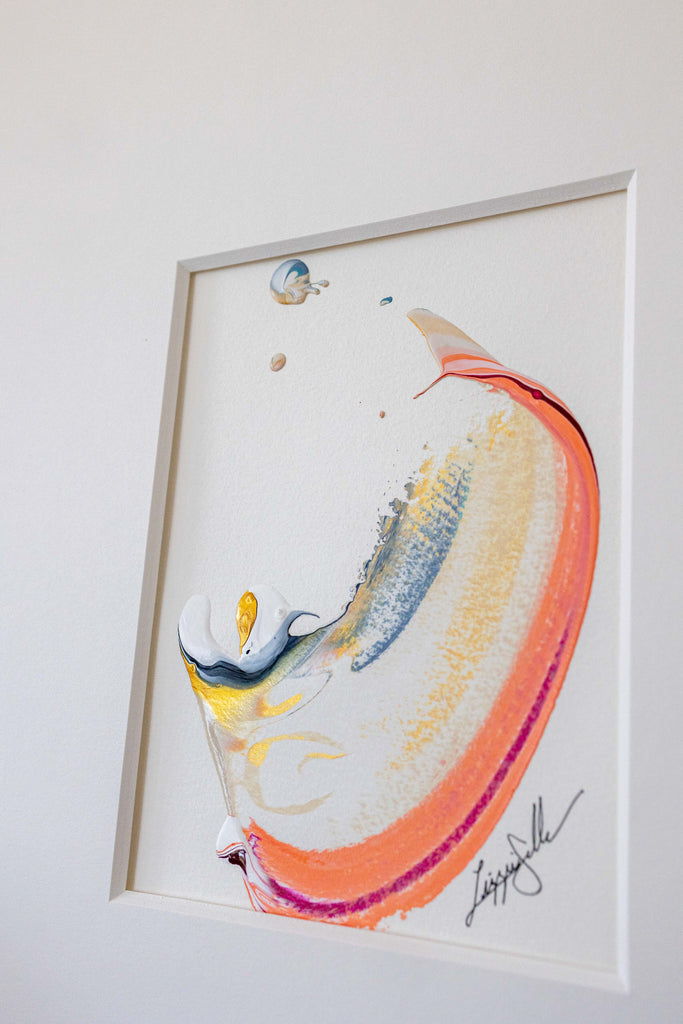An abstract framed painting featuring a curved, organic shape in orange, yellow, blue, and white, mounted on a light gray wall.