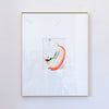 A framed abstract painting featuring a minimalist splash of orange, yellow, blue, and white paint on a white mat, enclosed in a thin gold frame and hung on a light gray wall.