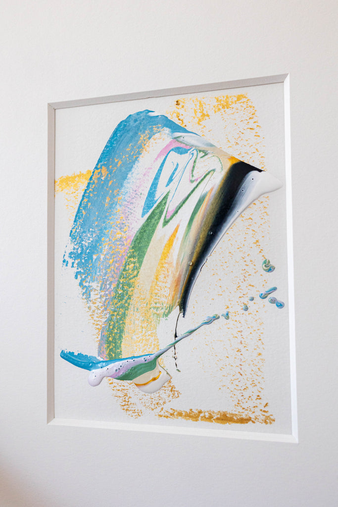 Abstract painting featuring blue, green, black, and gold in a white mat. Textural gold oil pastel markings