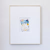 A framed abstract painting featuring blue, metallic gold, light pink, and black oil pastel markings, presented in a white mat and a thin gold frame against a light gray wall.