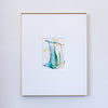 A framed painting featuring a central colorful composition of blue, green, and gold brushstrokes on a white mat, enclosed in a thin gold frame against a light gray wall.