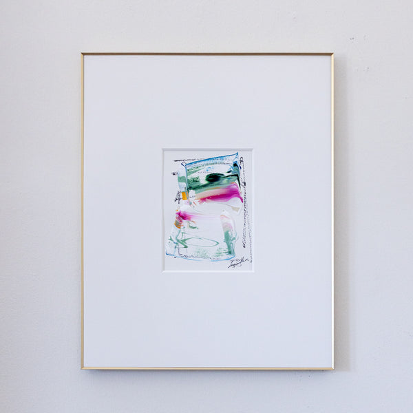A framed abstract painting featuring colorful acrylic brushstrokes, presented in a white mat and a thin gold frame against a light gray wall.