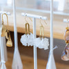Earring display with various earrings on a white stand.