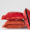 Stack of red textured pillows on a light gray background