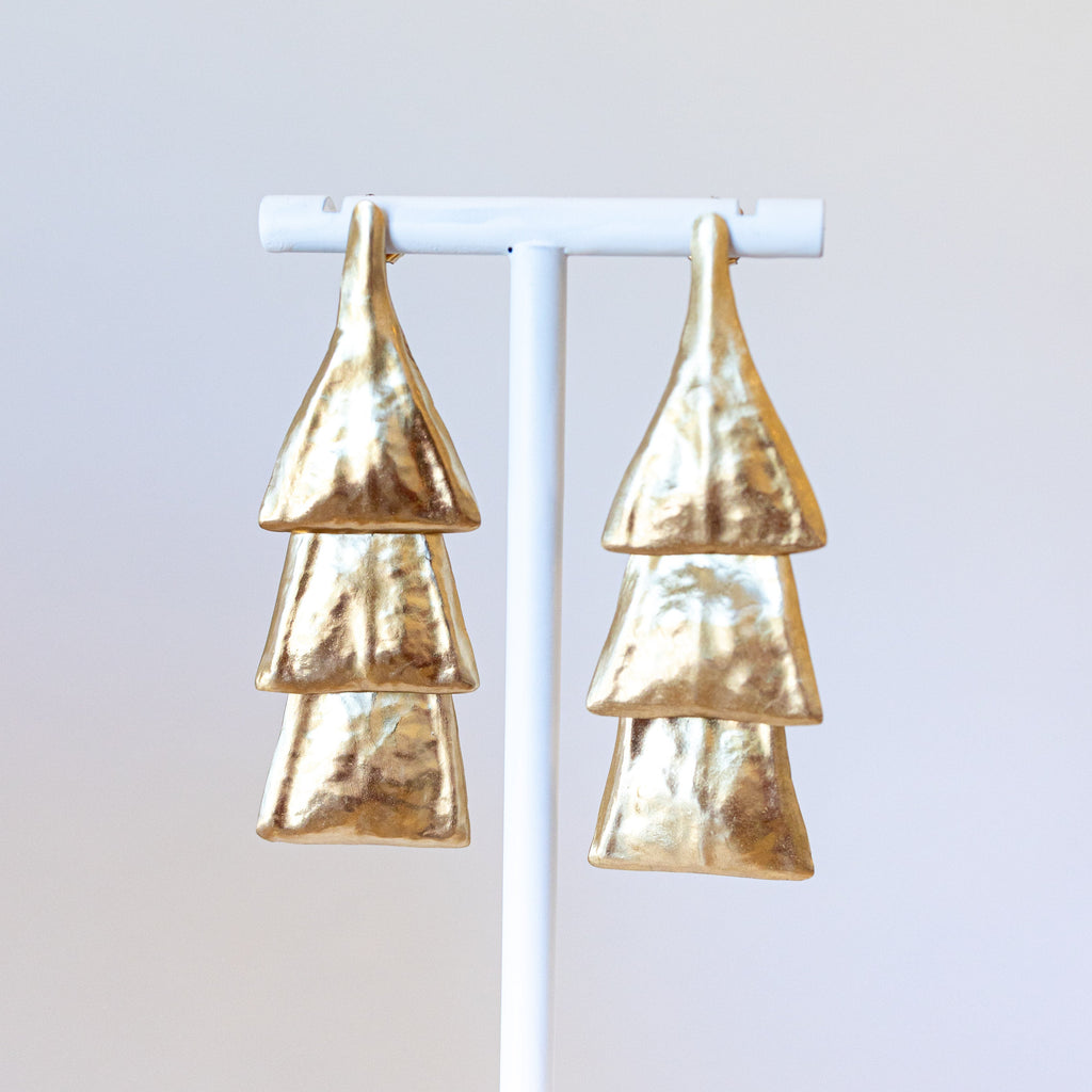 Pair of bronze earrings on a white stand against a light gray background