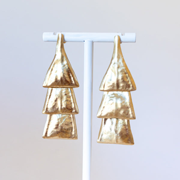 Pair of bronze earrings on a white stand against a light gray background