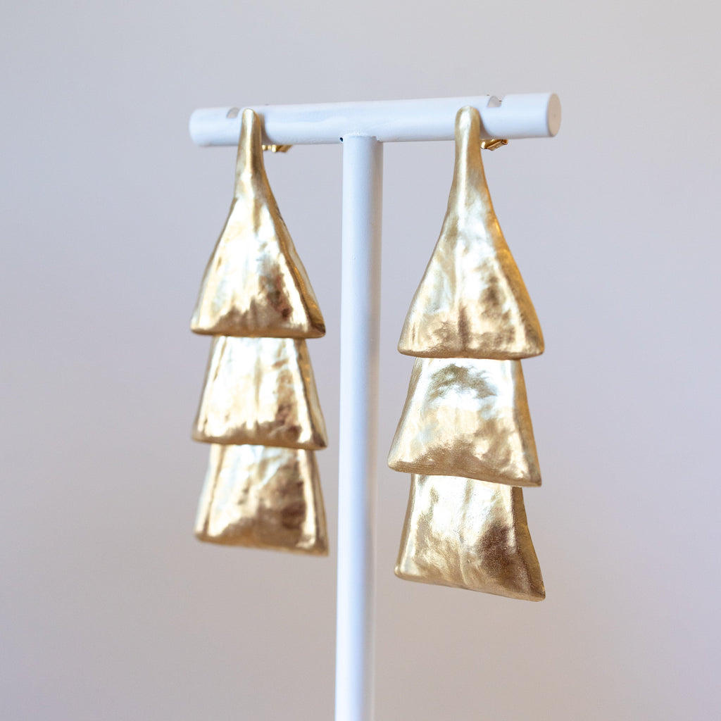 Bronze layered earrings on a white stand against a light gray background
