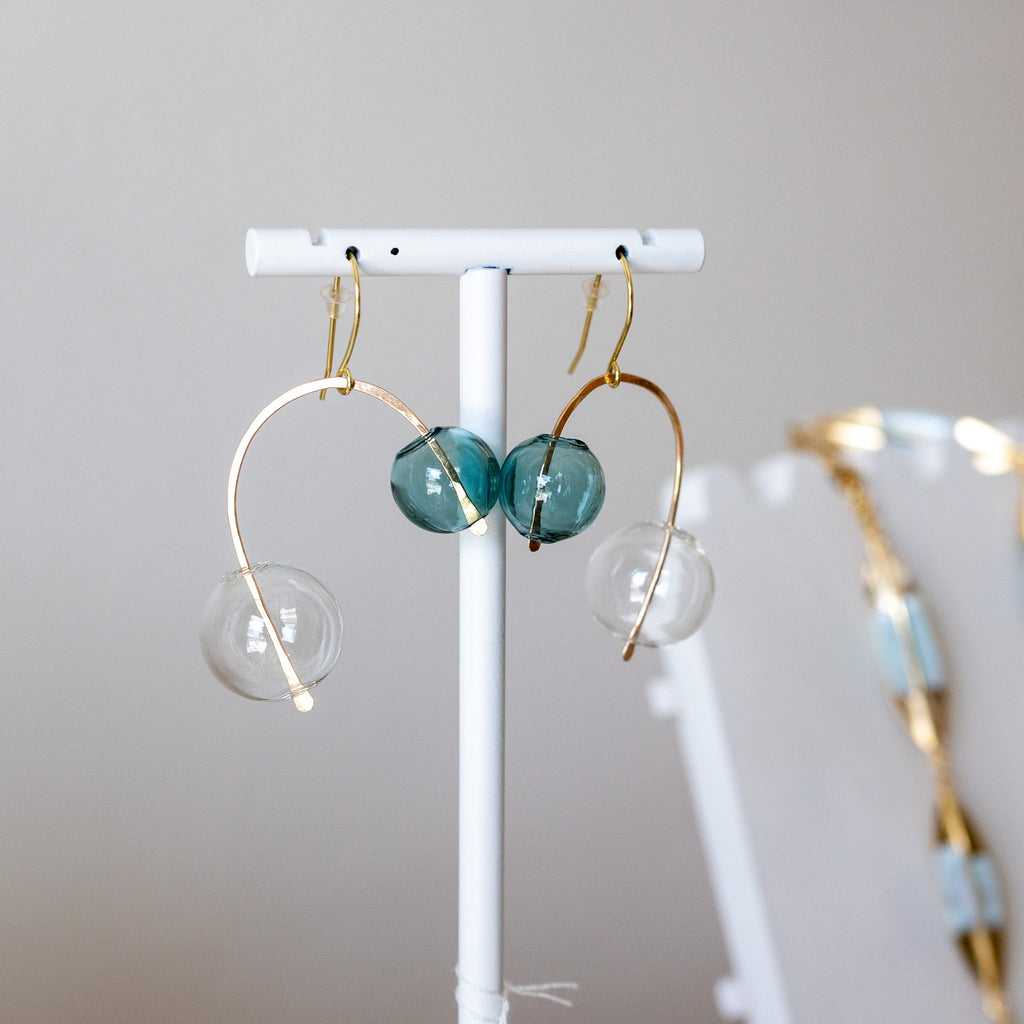 Glass ball Earrings on a white stand with a neutral background