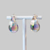 Teardrop-shaped earrings on a white stand with a blurred background