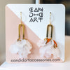 Gold earrings with floral designs on a branded card