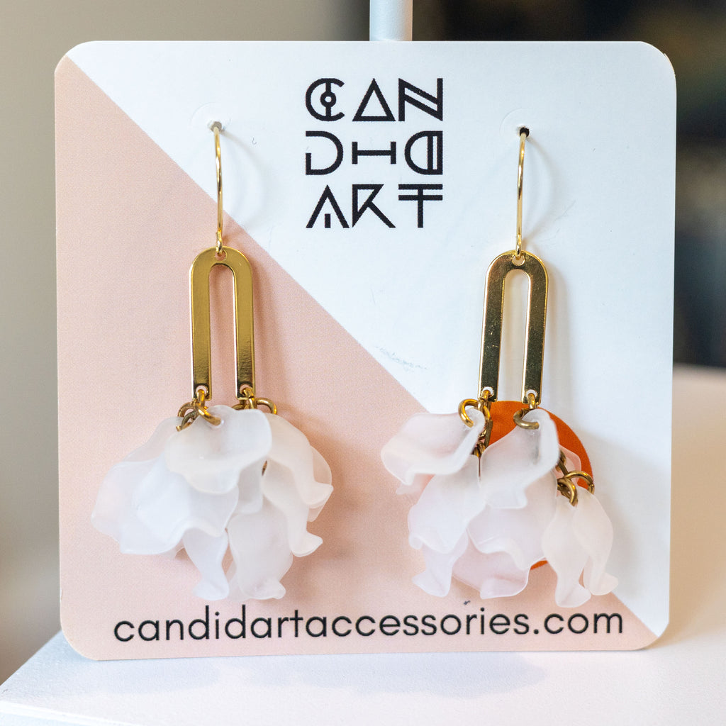 Gold earrings with floral designs on a branded card