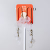 A pair of dangling earrings with translucent pale pink flower-shaped charms and gold-toned chains, displayed on an orange card mounted on a white stand against a light gray background.