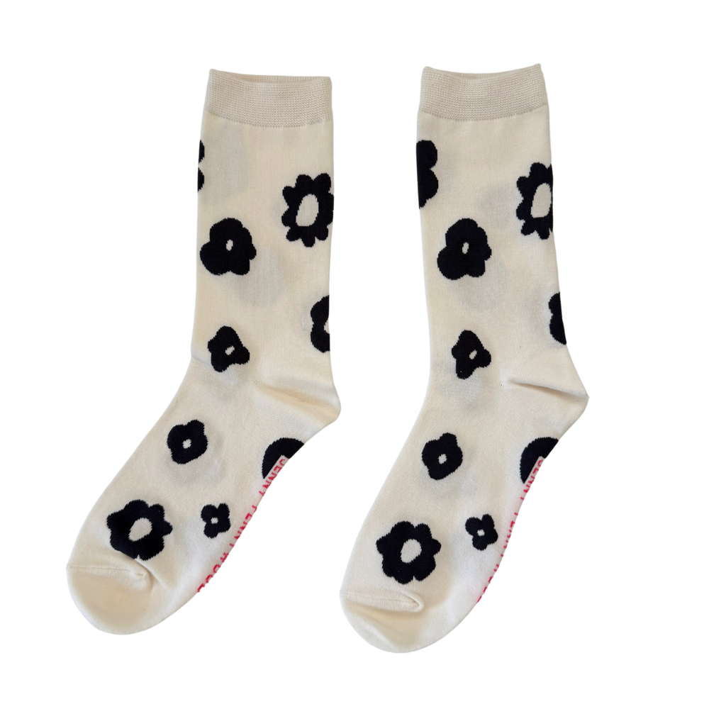 Pair of cream socks with black flower patterns on a white background