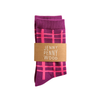 A pair of folded purple socks with a pink plaid pattern, wrapped in a brown paper band that reads 'JENNY PENNY WOOD' in white text, on a solid white background.