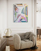 Beige armchair with a blanket, side table, and abstract painting on a white wall.