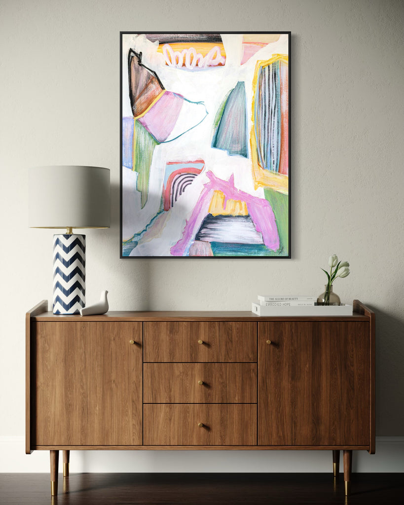 Wooden sideboard with abstract art and decorative items against a gray wall