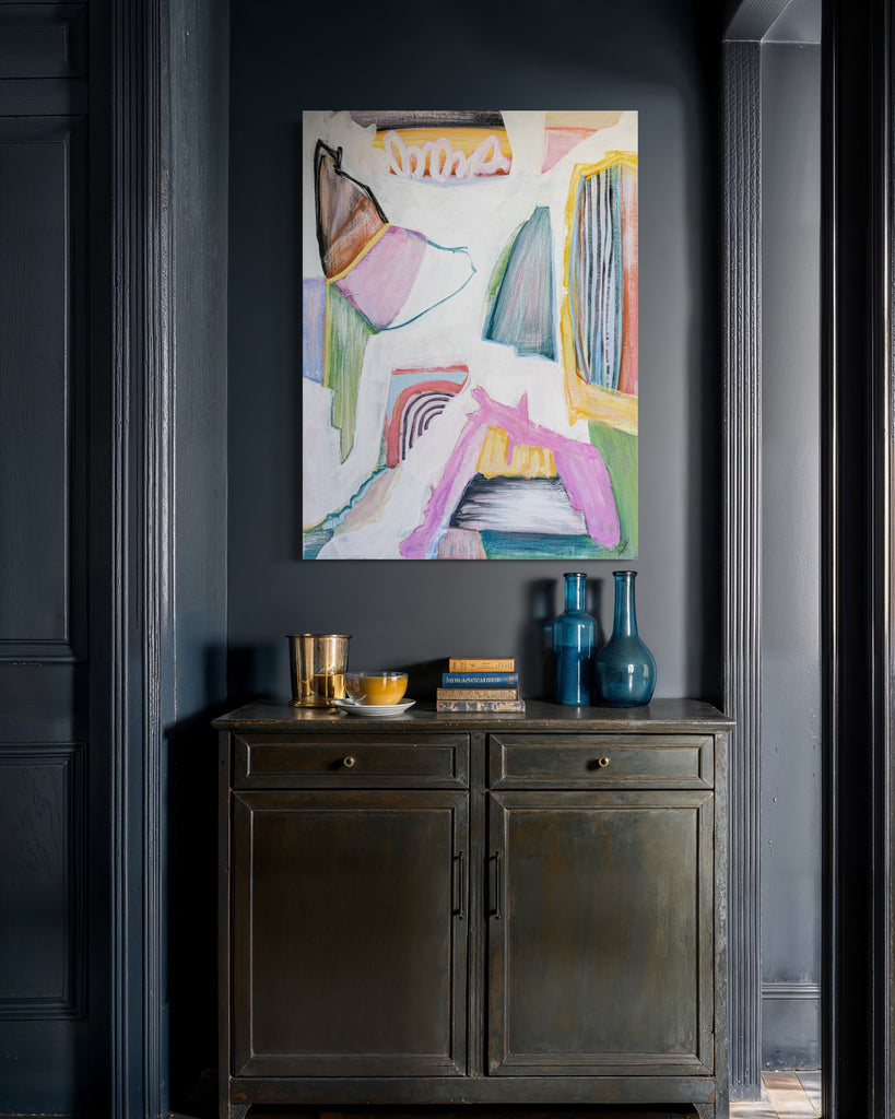 Abstract painting on a dark wall above a wooden cabinet with decorative items.
