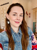 Woman with long brown hair wearing a denim jacket in an indoor setting