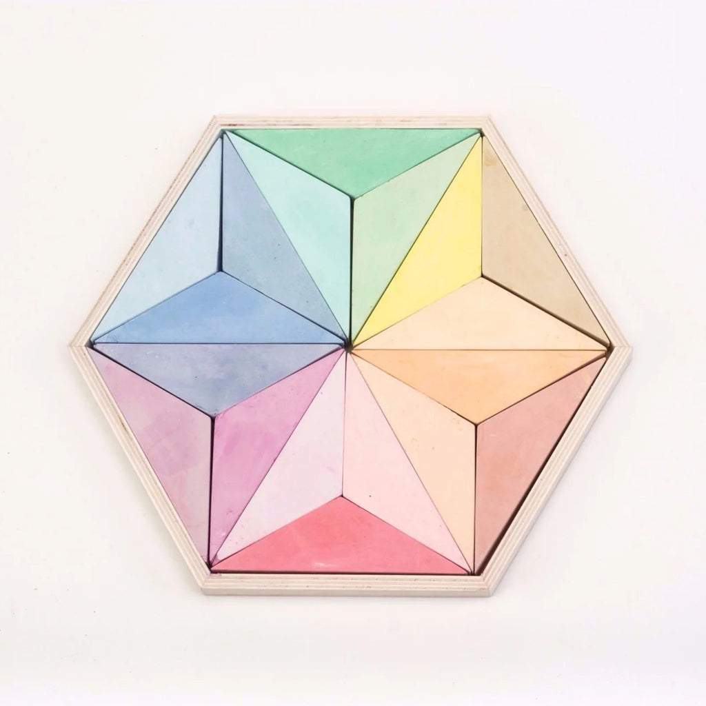 A hexagonal wooden board featuring six pastel-colored triangular sections arranged in a geometric star pattern, photographed against a clean white background.