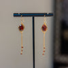 Pair of earrings on a black stand against a neutral background