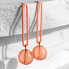 Coral-colored earrings with spherical drops on a textured white surface.