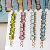 Set of floral beaded earrings on a white card with a colorful abstract background.