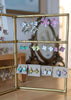 Gold earring stand with floral earrings on a wooden surface