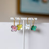 Flower-shaped earrings on a white stand with a blurred background