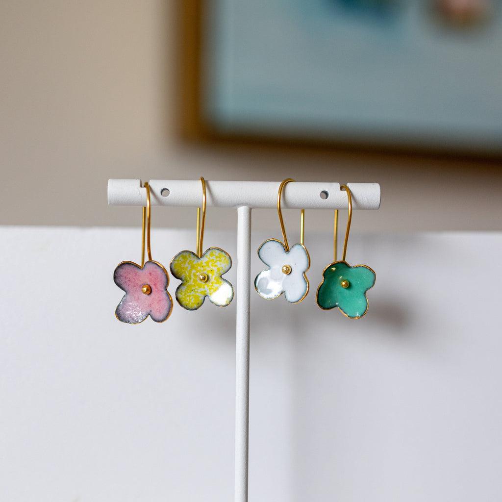 Flower-shaped earrings on a white stand with a blurred background