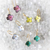Set of colorful flower-shaped earrings on a textured white surface