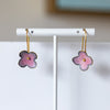 Flower-shaped earrings on a white stand with a neutral background