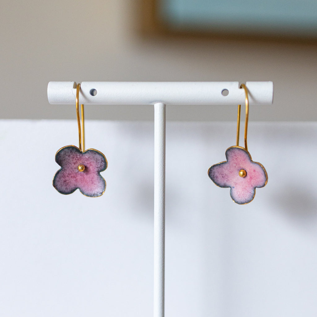 Flower-shaped earrings on a white stand with a neutral background