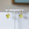 Flower-shaped earrings on a white stand with a neutral background