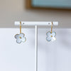 Flower-shaped earrings on a white stand with a blurred background