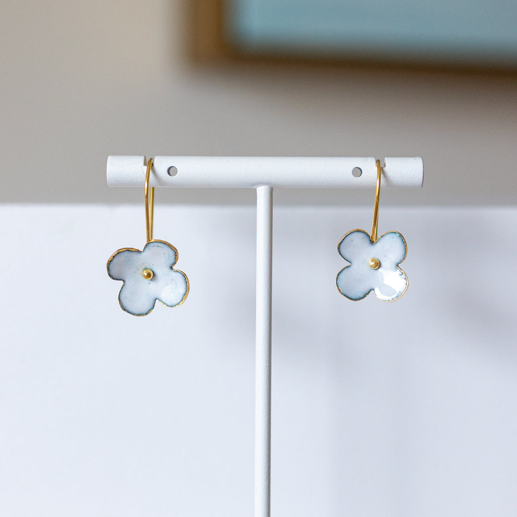 Flower-shaped earrings on a white stand with a blurred background