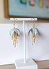 Pair of earrings on a white stand with a blurred background