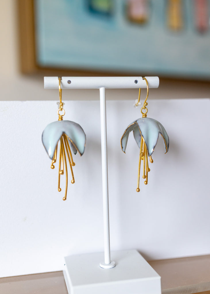 Pair of earrings on a white stand with a blurred background
