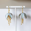 Pair of earrings on a white stand against a light background