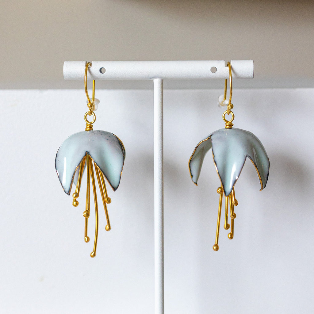 Pair of earrings on a white stand against a light background