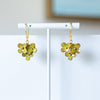 Gold floral earrings on a white stand with a neutral background