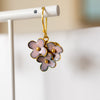 Floral earrings with gold accents on a white stand against a neutral background